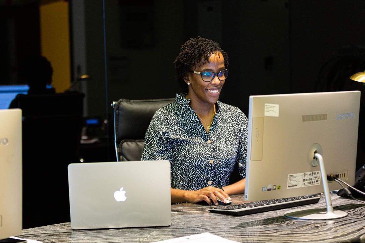A woman smiling while working on a computer, highlighting the benefits of a virtual office setup in Dubai by myOffice.