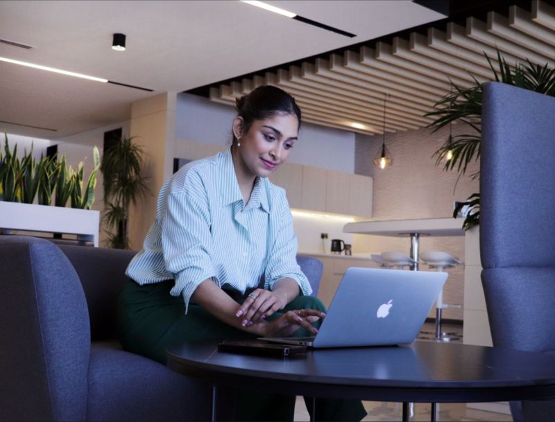 myOffice space for company formation in Dubai, featuring a professional woman working on her laptop in a modern office environment