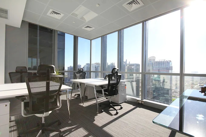 Modern office with large windows offering a city view, featuring managed office desks and ergonomic chairs by myOffice.